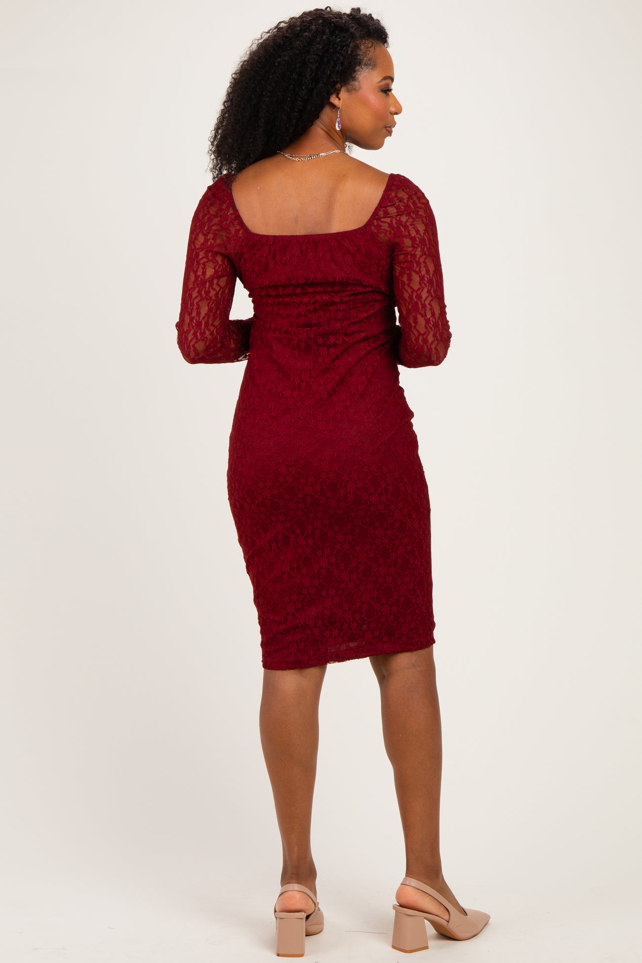 woman wearing a burgundy lace long sleeve bodycon dress from the back with a scooped neckline