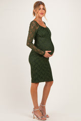 woman wearing a dark green lace maternity dress, fitted style, showing her baby bump with long sleeves and a sweetheart neckline