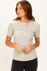woman wearing a light gray ribbed short sleeve top with a round neckline and relaxed fit
