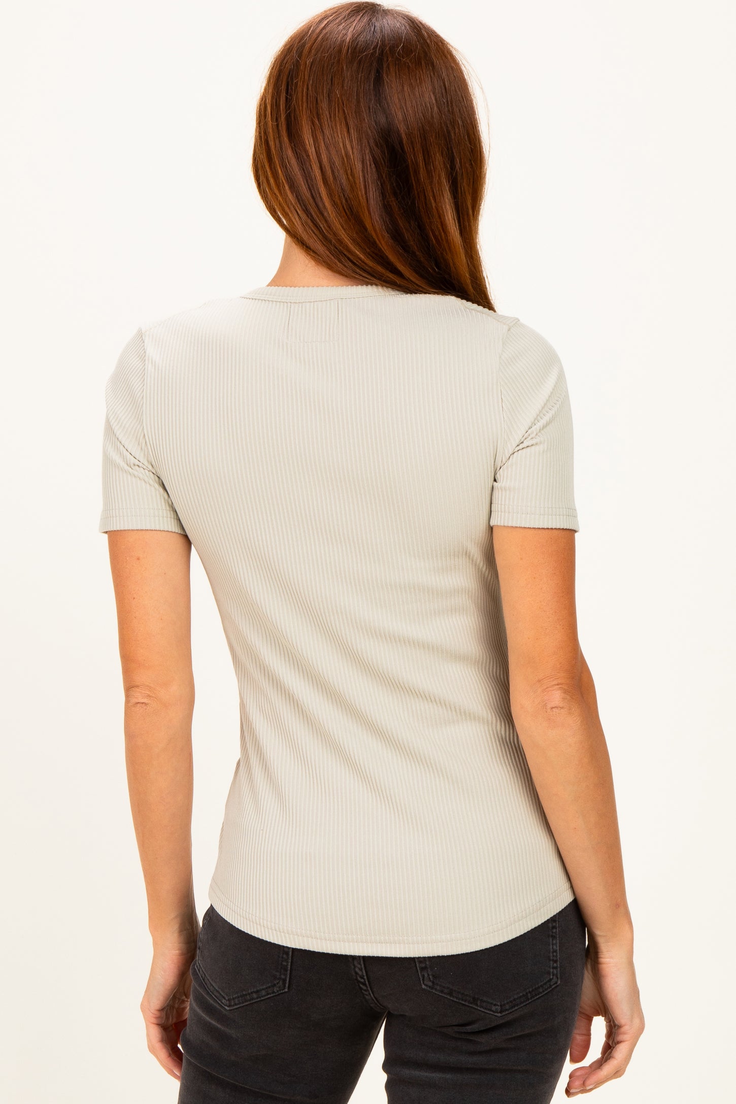 woman wearing a light gray ribbed short sleeve top, seen from the back, styled with dark jeans