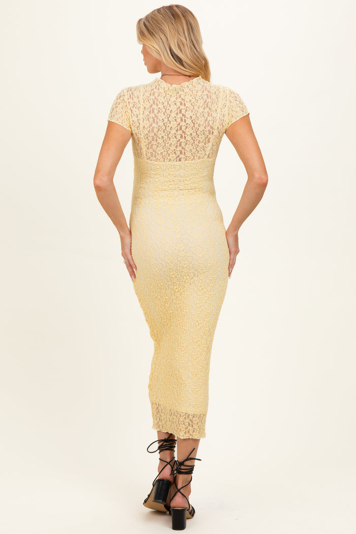 woman wearing a yellow lace maternity dress with short sleeves and a fitted silhouette, showing a pregnant belly