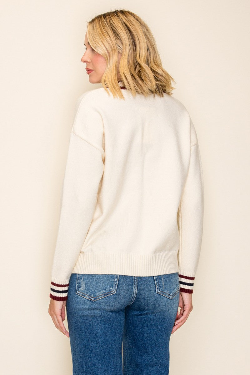 woman wearing a cream colored sweater with striped cuffs and blue jeans, shown from the back