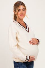 woman wearing a cream maternity sweater with burgundy stripes and a v-neck, showing her baby bump