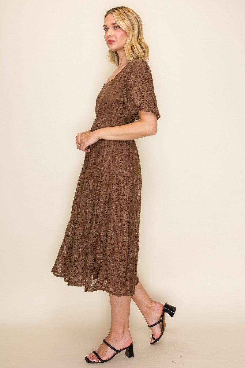 woman wearing a brown lace midi dress with short sleeves and a fitted waist, standing sideways