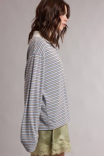 woman wearing a striped long sleeve top with a relaxed fit and balloon sleeves, paired with a light green skirt with lace trim
