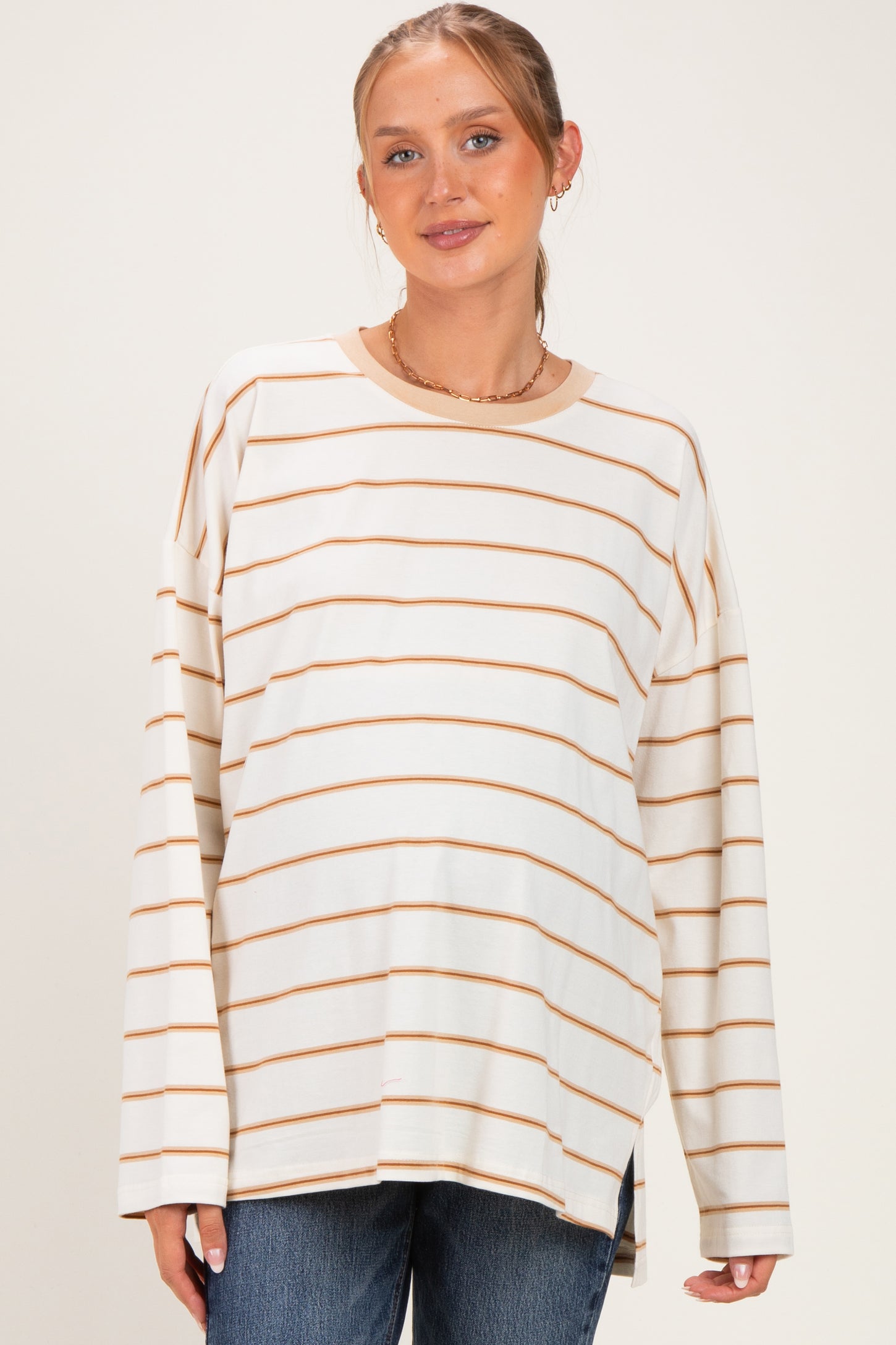 woman wearing a cream and caramel striped maternity top with a relaxed fit and visible baby bump
