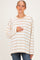 woman wearing a cream and brown striped maternity top and holding her baby bump