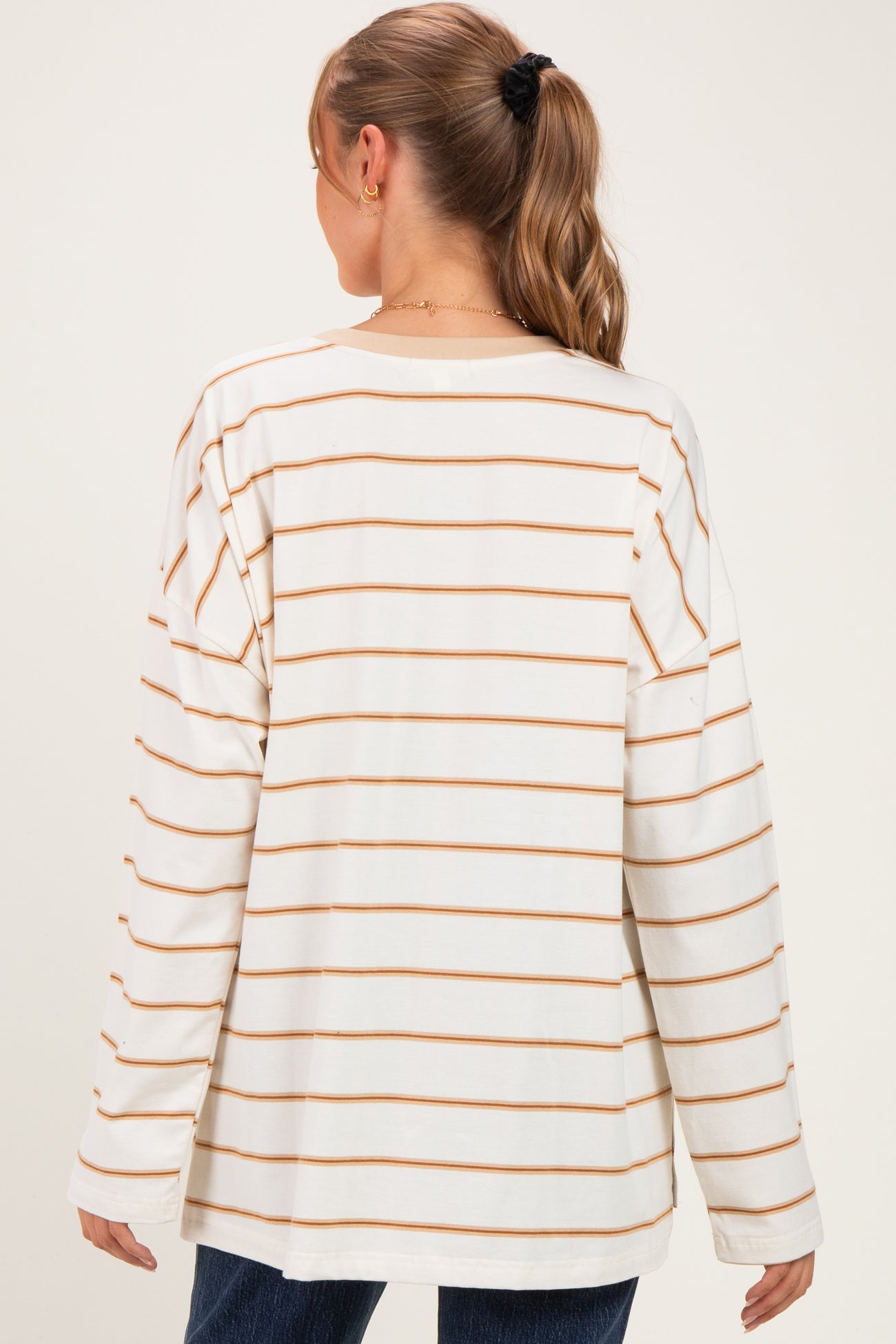 woman wearing a beige and cream striped long sleeve maternity top viewed from the back