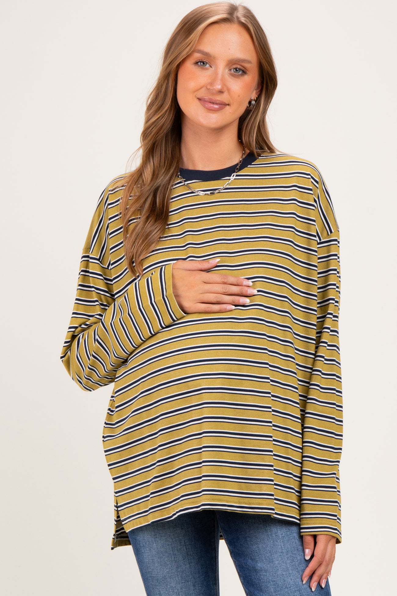 woman wearing a yellow and navy striped maternity top and holding her baby bump