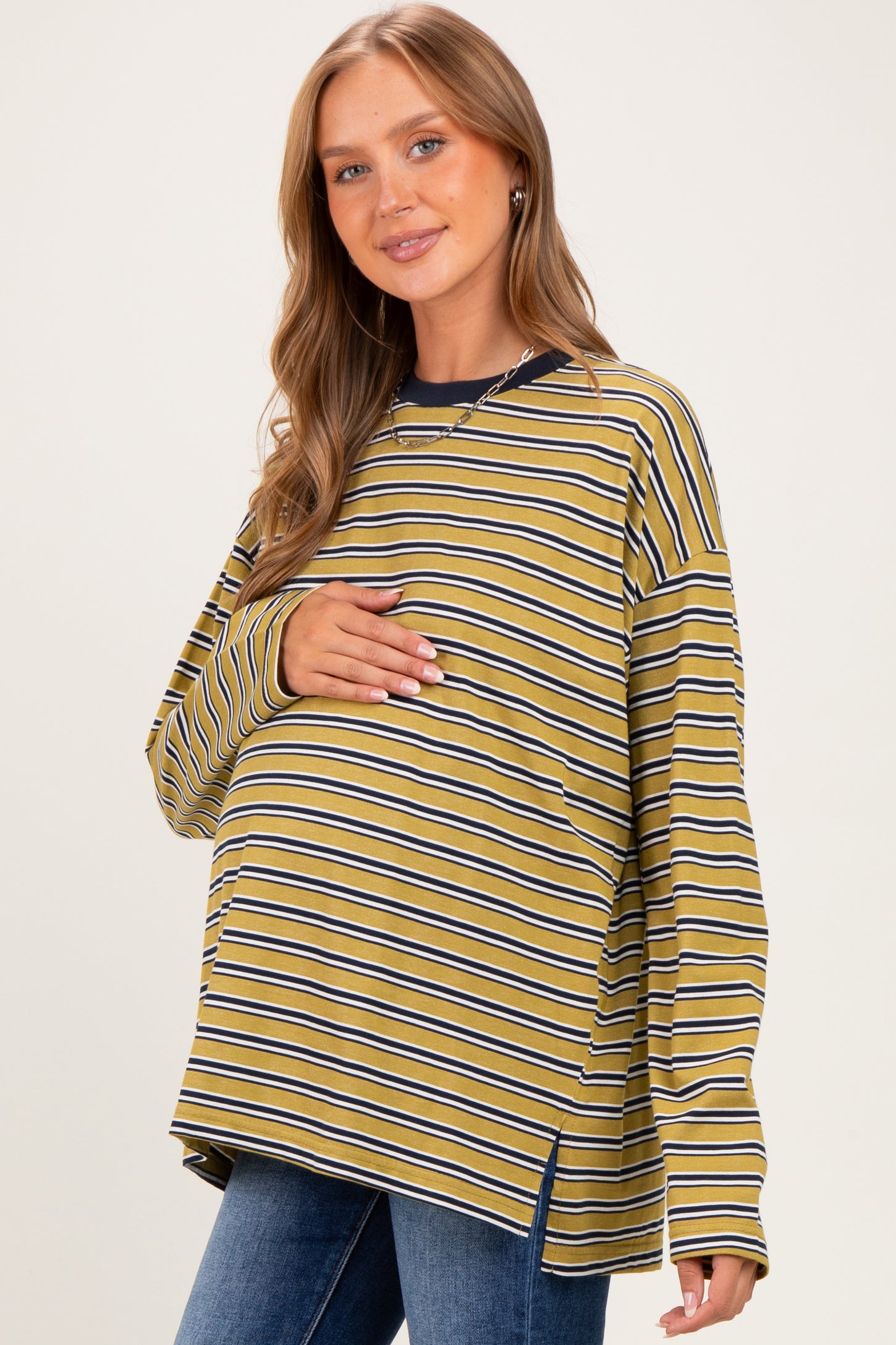 woman wearing a mustard yellow and navy striped maternity top and holding her baby bump