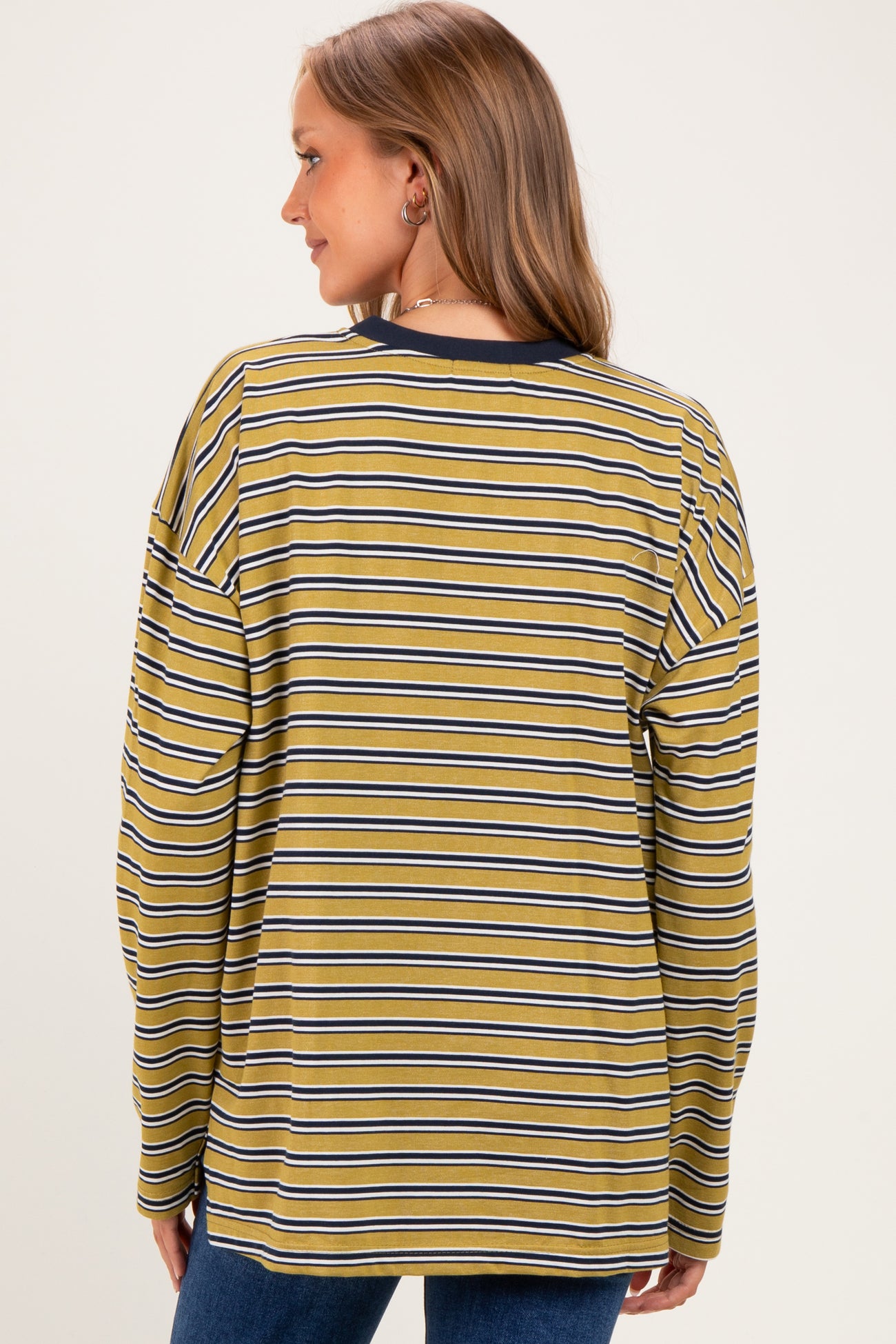 woman wearing a mustard yellow and navy striped maternity top with long sleeves and a relaxed fit, showing her back