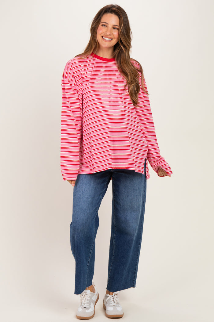 woman wearing a pink and red striped maternity top with long sleeves paired with wide-leg blue jeans