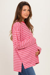 woman wearing a pink and white striped long sleeve maternity top and holding her baby bump