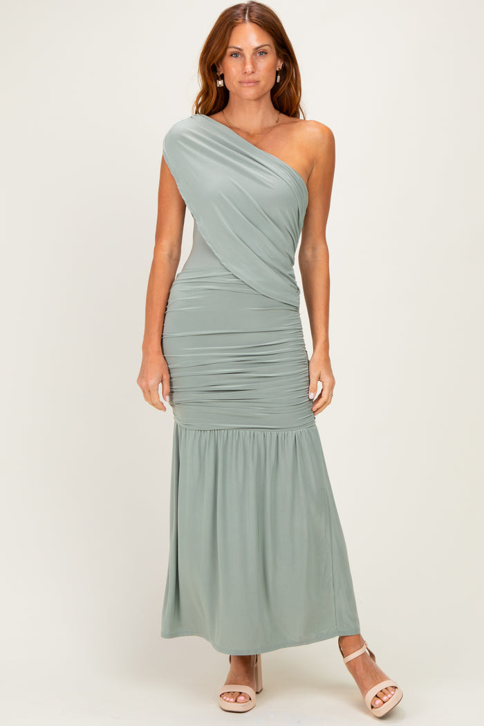 woman wearing a sage green one-shoulder maxi dress with ruching and a flowy bottom