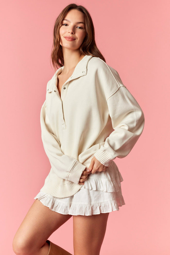 woman wearing a cream oversized pullover sweatshirt and a white ruffled mini skirt