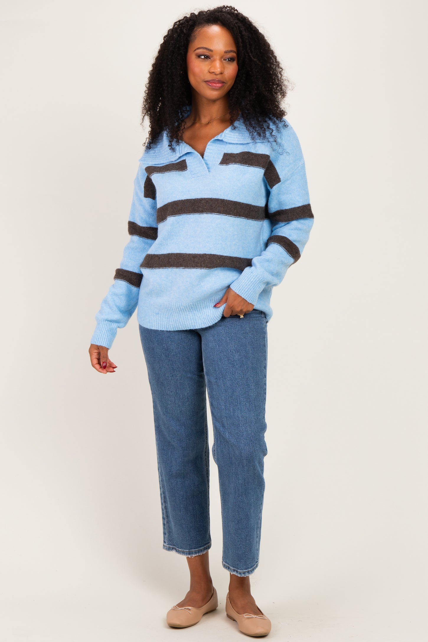 woman wearing a light blue and brown striped sweater with a collar and blue jeans