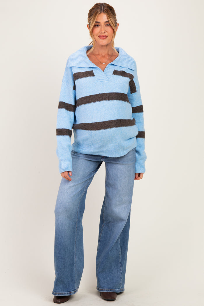 woman wearing a light blue and dark brown striped maternity sweater and blue flared jeans, showing a baby bump
