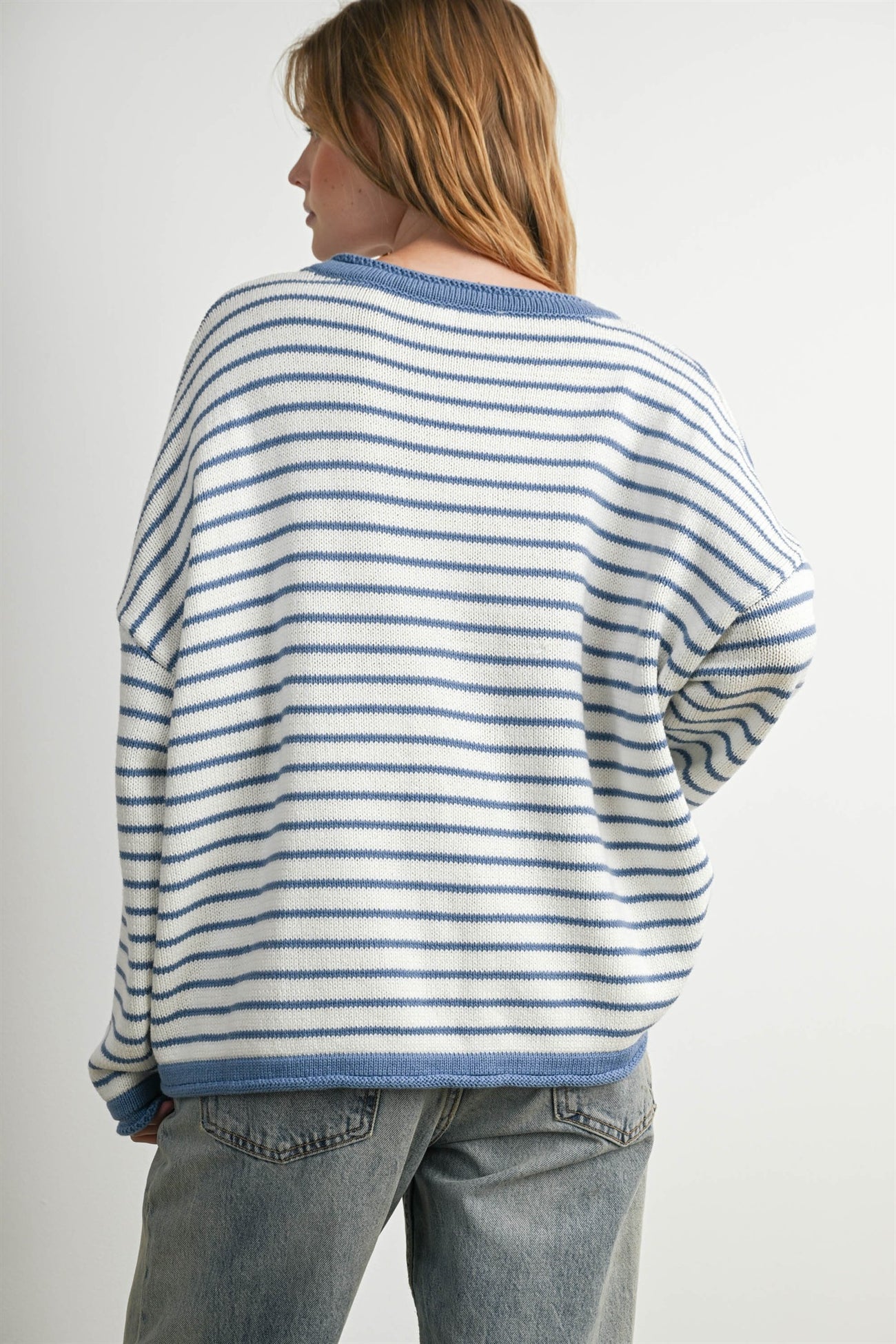 woman wearing a relaxed fit white and blue striped sweater with dropped shoulders and a round neckline, viewed from behind