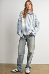 woman wearing a blue and white striped oversized sweater with blue trim and light wash baggy jeans