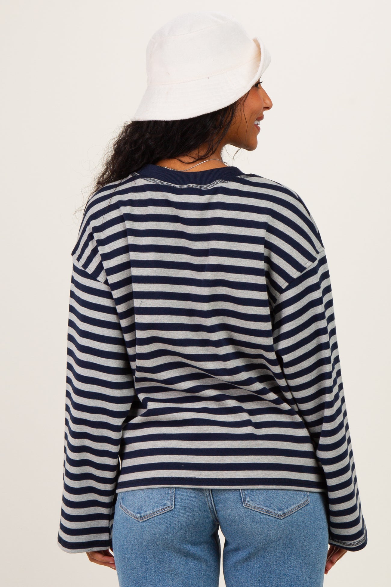woman wearing a navy and gray striped maternity top with long sleeves and relaxed fit, seen from the back