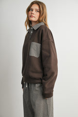 woman wearing a brown pullover sweatshirt with a checkered pocket and collar, styled with checkered pants