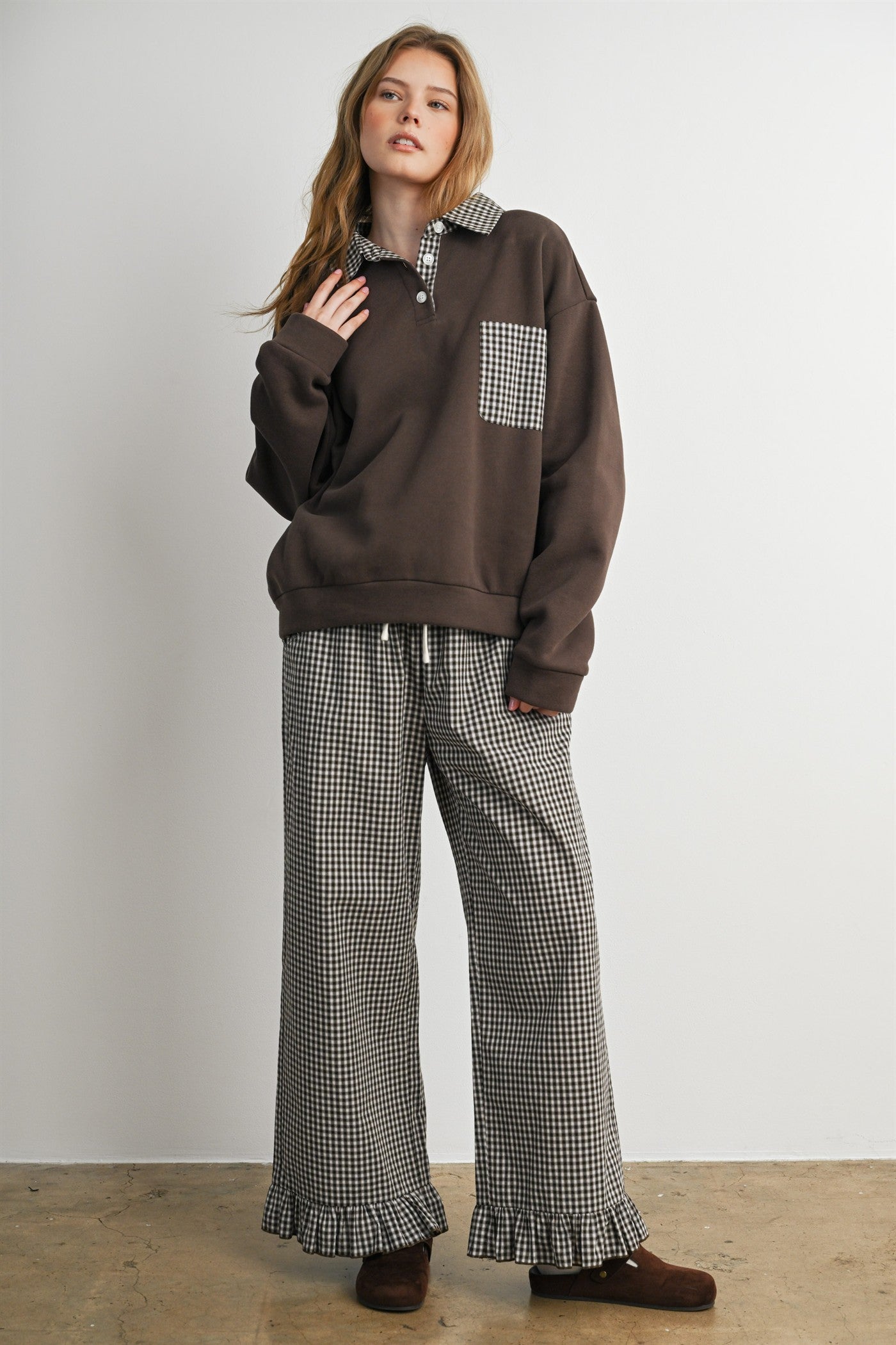 woman wearing a brown oversized sweatshirt with a checkered collar and matching checkered wide-leg pants