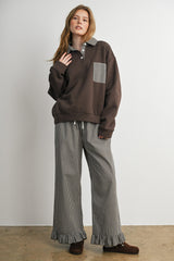 woman wearing a brown oversized sweatshirt with a checkered collar and matching checkered wide-leg pants