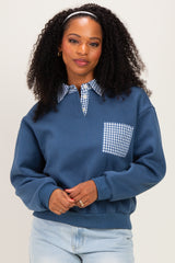 woman wearing a dark blue sweatshirt with a gingham collar and pocket, styled with light denim jeans