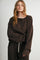 woman wearing a brown polka dot long sleeve top with a henley neckline and relaxed fit