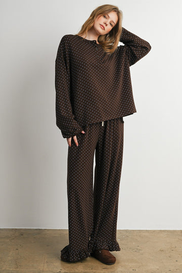 woman wearing a brown polka dot loungewear set with long sleeves and wide-leg pants