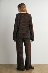 woman wearing a brown polka dot loungewear set with long sleeves and flared pants, seen from the back
