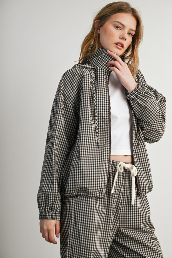 woman wearing a black and white checked zip-up jacket with a high collar and matching pants