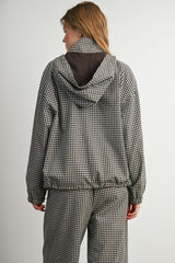 woman wearing a black and white checkered jacket with a hood, facing away from the camera