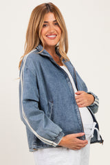 woman wearing a light blue denim maternity jacket with white side stripes and holding her baby bump