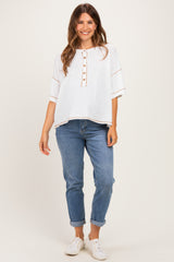 woman wearing a white maternity top with button details and rolled sleeves paired with light blue jeans