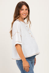 woman wearing a white maternity top with button details and cap sleeves, showing her baby bump