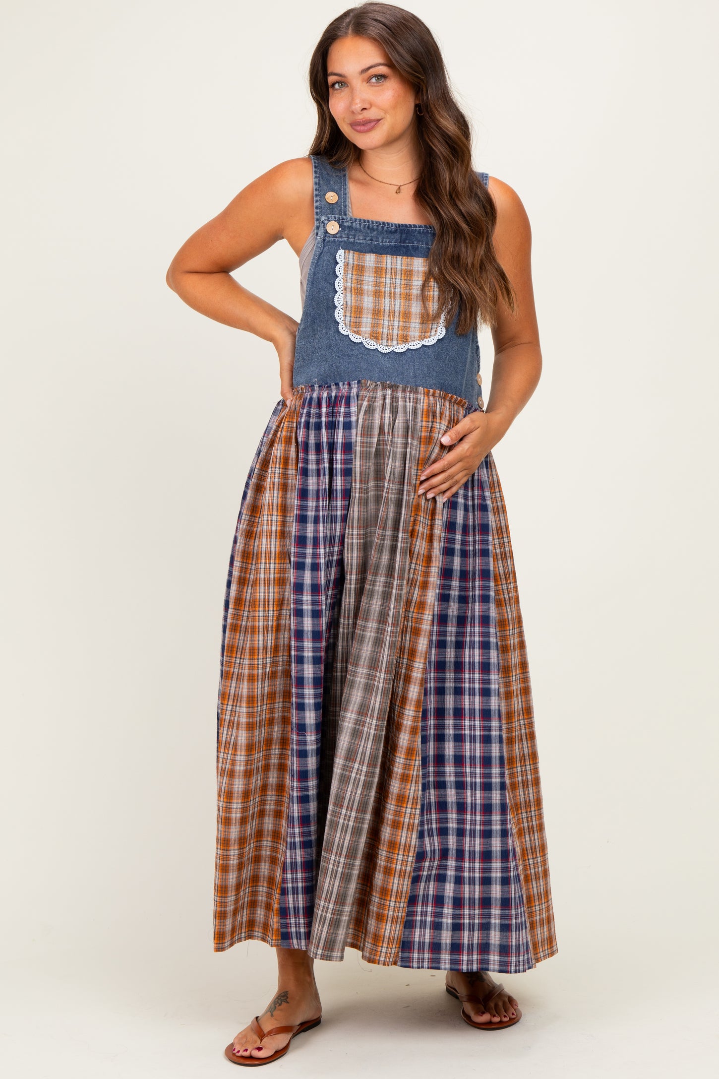 woman wearing a plaid maternity maxi dress with denim top and holding her baby bump