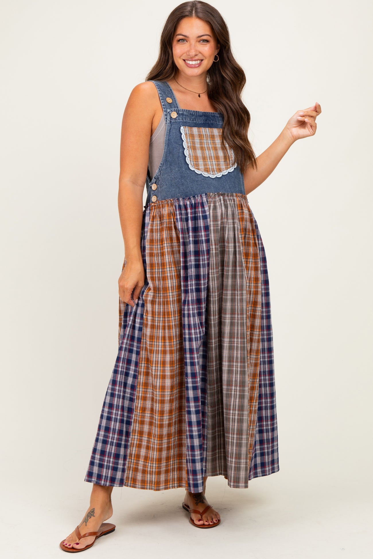 woman wearing a denim and plaid maternity dress with a fitted top and flowy skirt, showcasing a baby bump