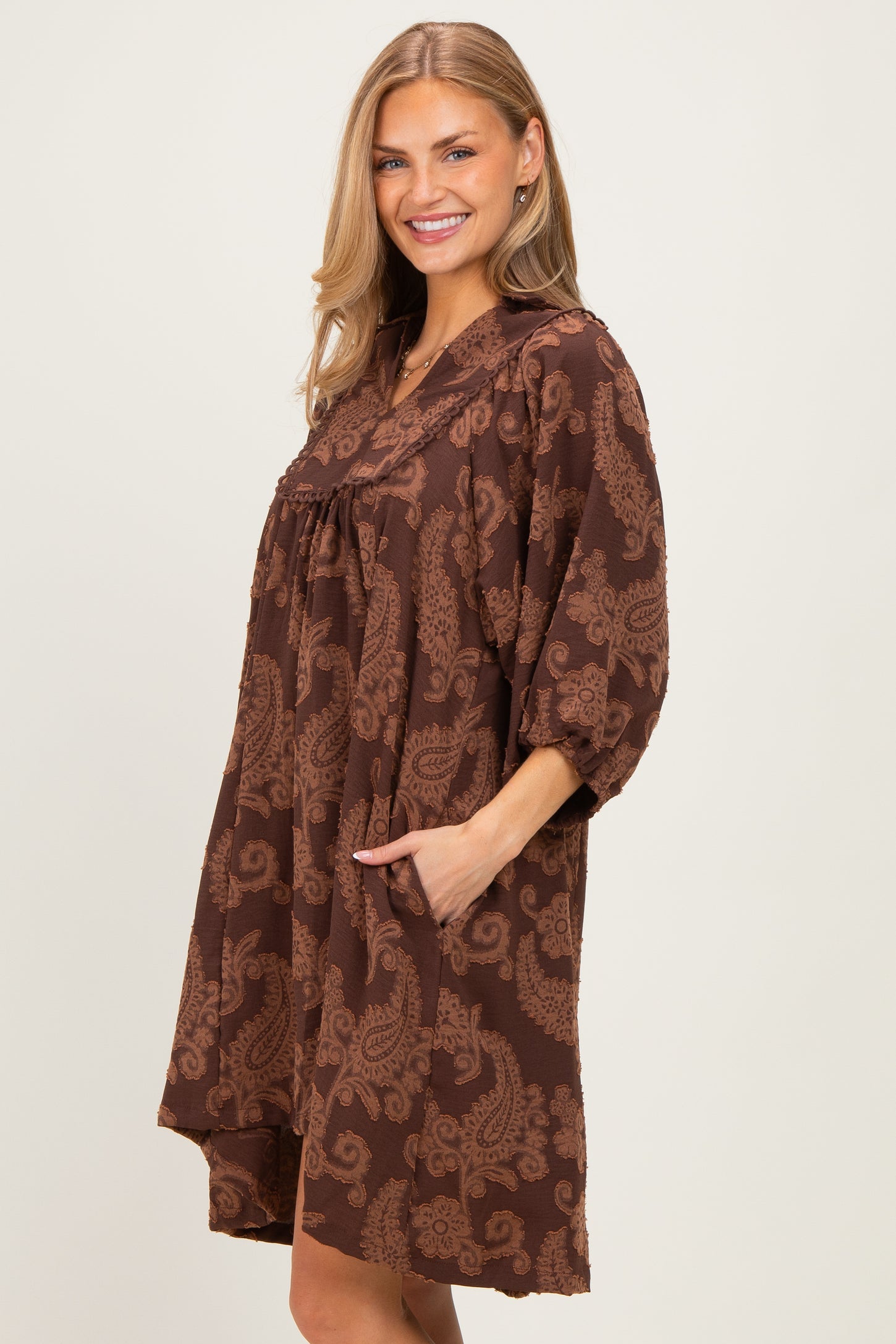 woman wearing a brown paisley print oversized dress with pockets and three-quarter sleeves