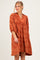woman wearing an orange paisley print dress with a collar and puff sleeves