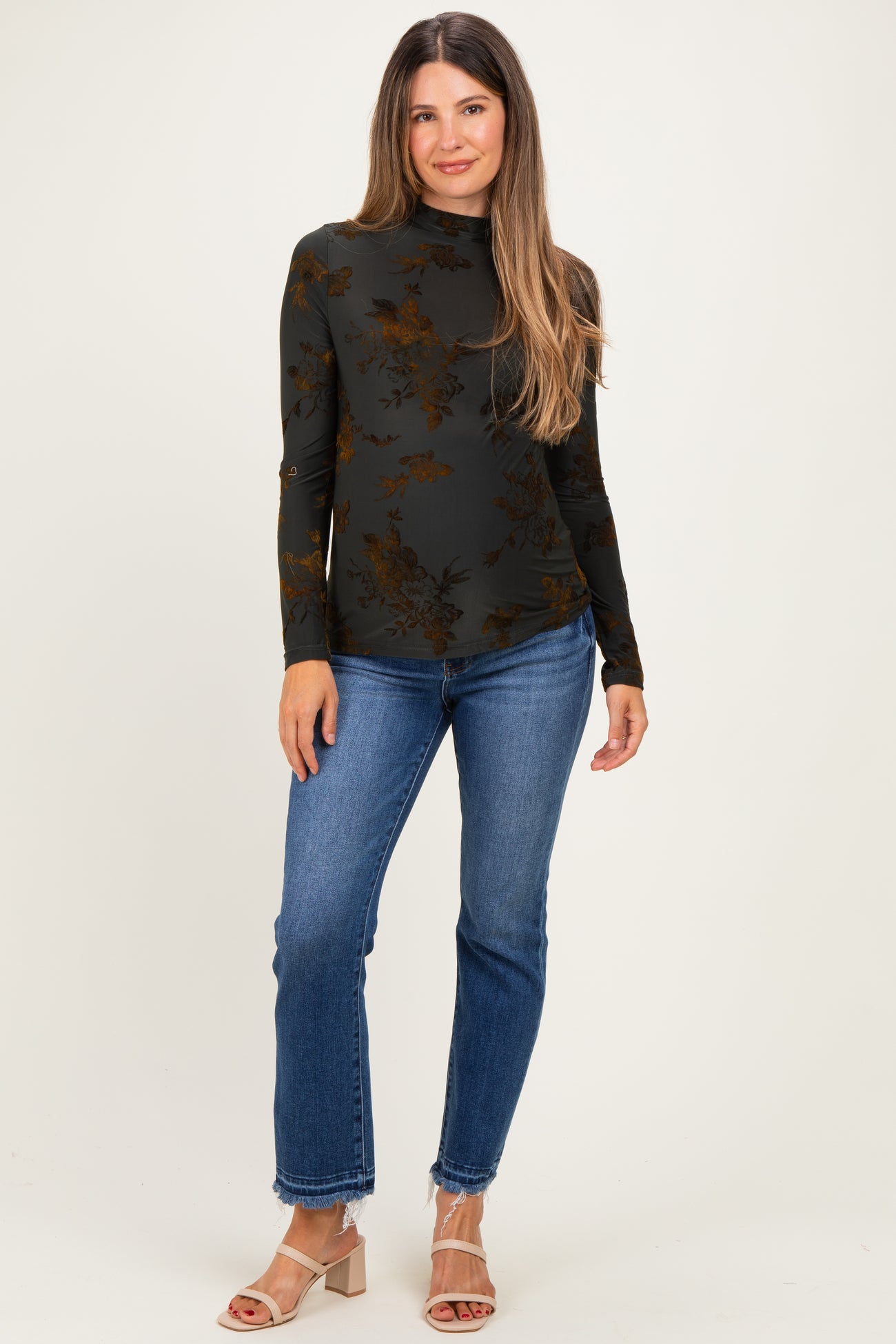 woman wearing a black floral maternity top with a high neck and long sleeves, paired with blue jeans