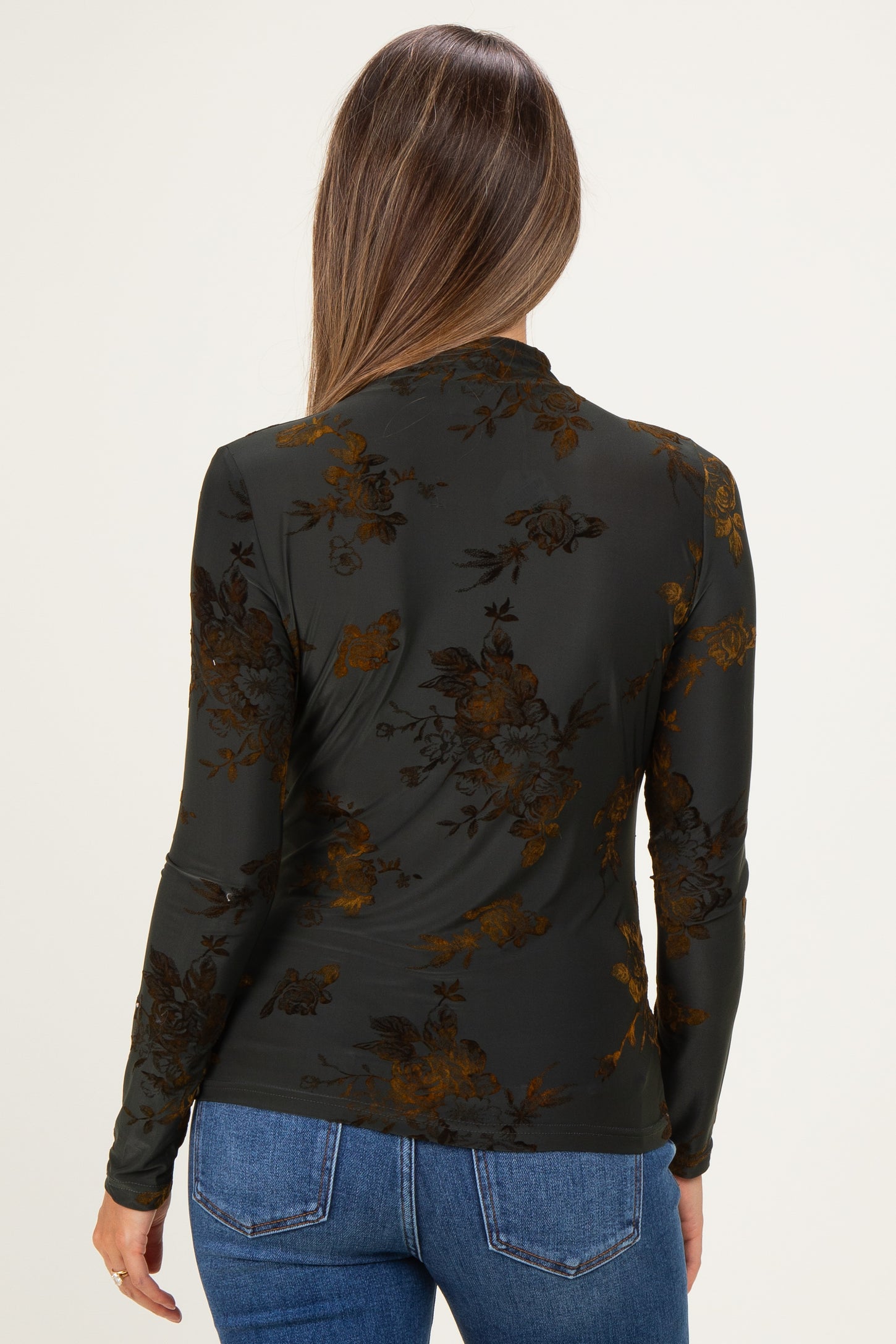 woman wearing a dark floral maternity top with long sleeves, seen from the back, paired with blue jeans