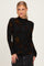 woman wearing a black long sleeve top with a fall floral pattern and a mock neck, styled with a denim skirt