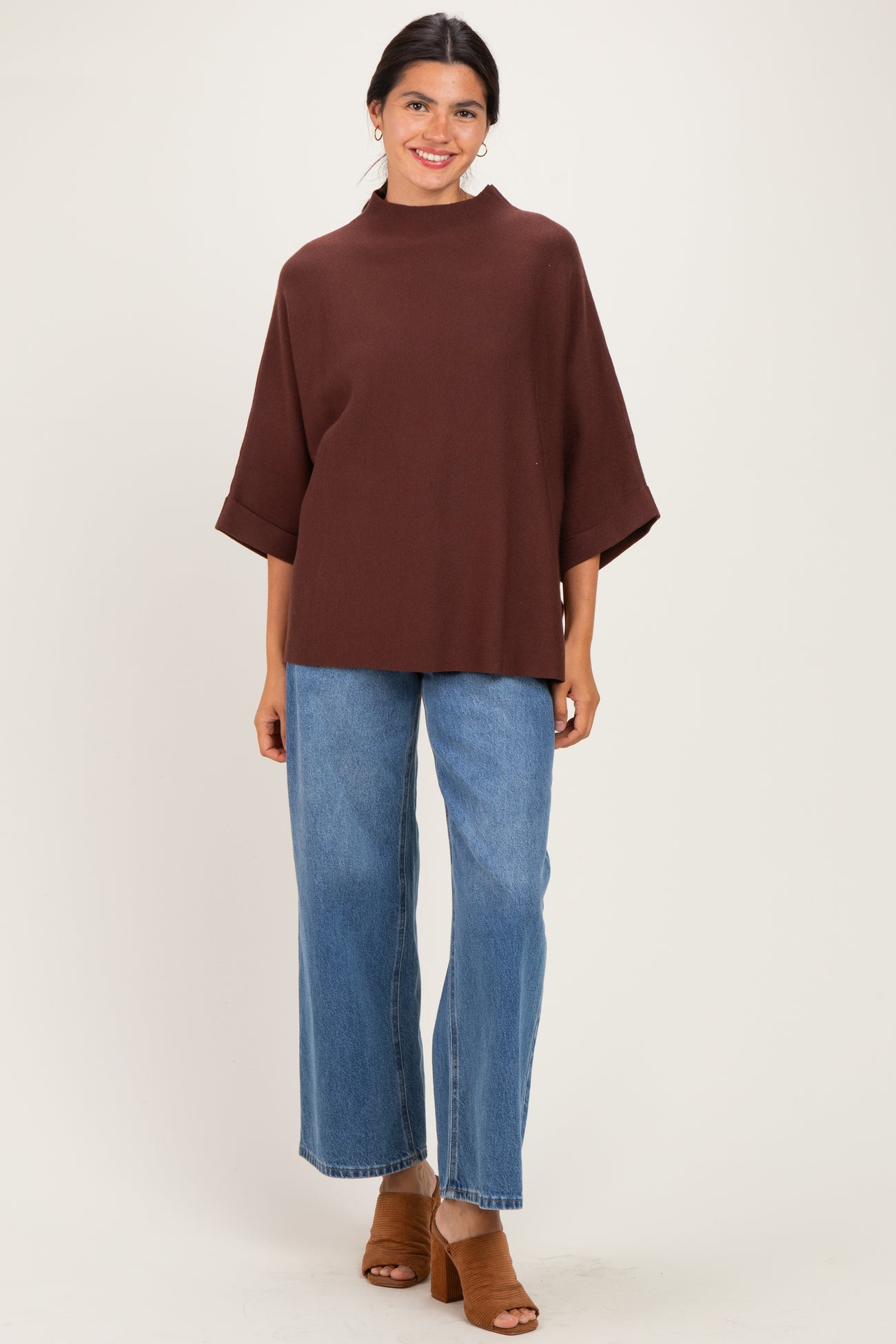woman wearing a brown oversized top with half sleeves and high-waisted blue wide-leg jeans