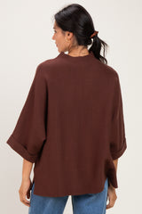 woman wearing a brown oversized knit top with rolled sleeves and back neckline detail
