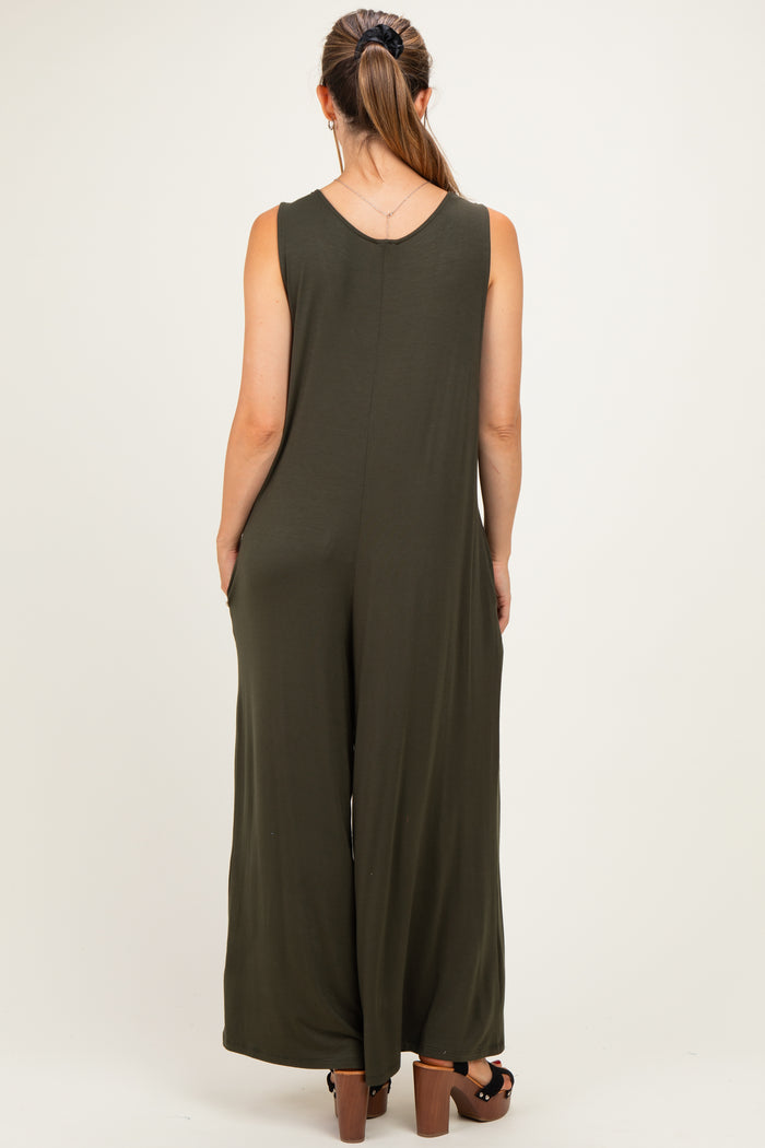 woman wearing an olive green maternity jumpsuit with a loose fit and wide legs, viewed from the back