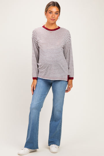 woman wearing a striped maternity top with red trim and jeans, showing a baby bump