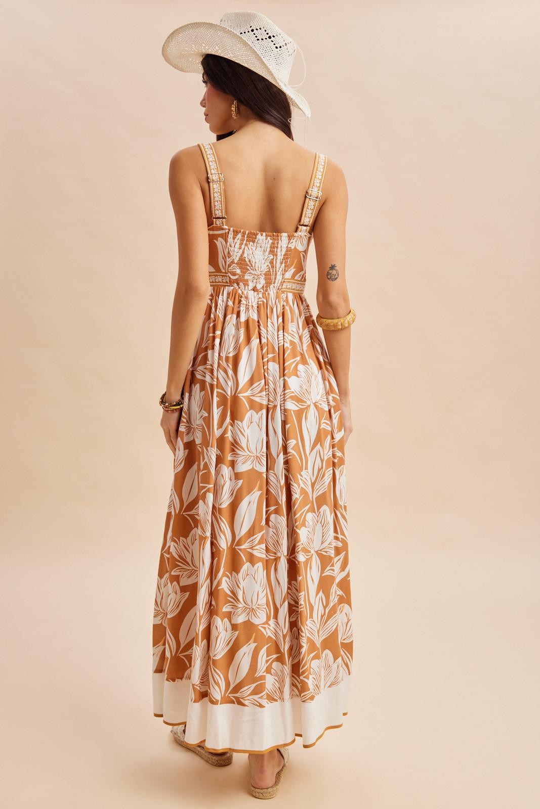 woman wearing a back view of a brown floral maxi dress with adjustable straps and a smocked bodice