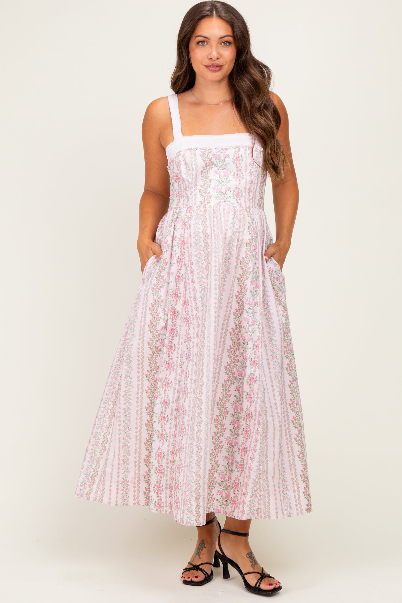 woman wearing a floral patterned white maternity maxi dress with pockets and a square neckline