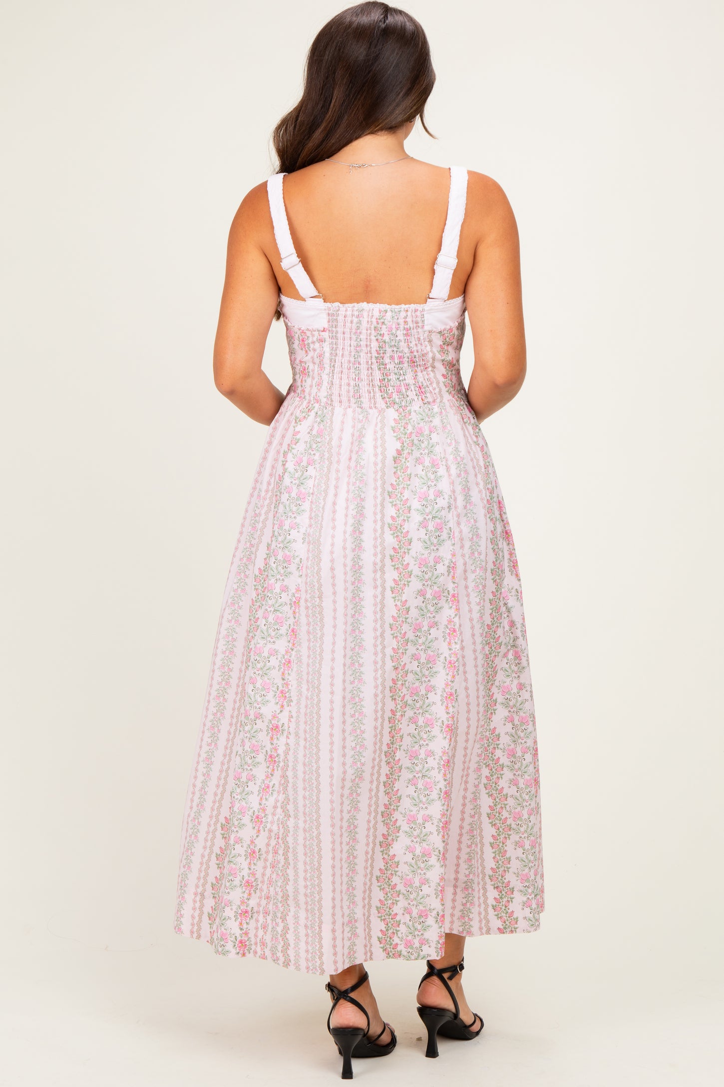 woman wearing a pink floral maternity maxi dress with a smocked back and adjustable straps